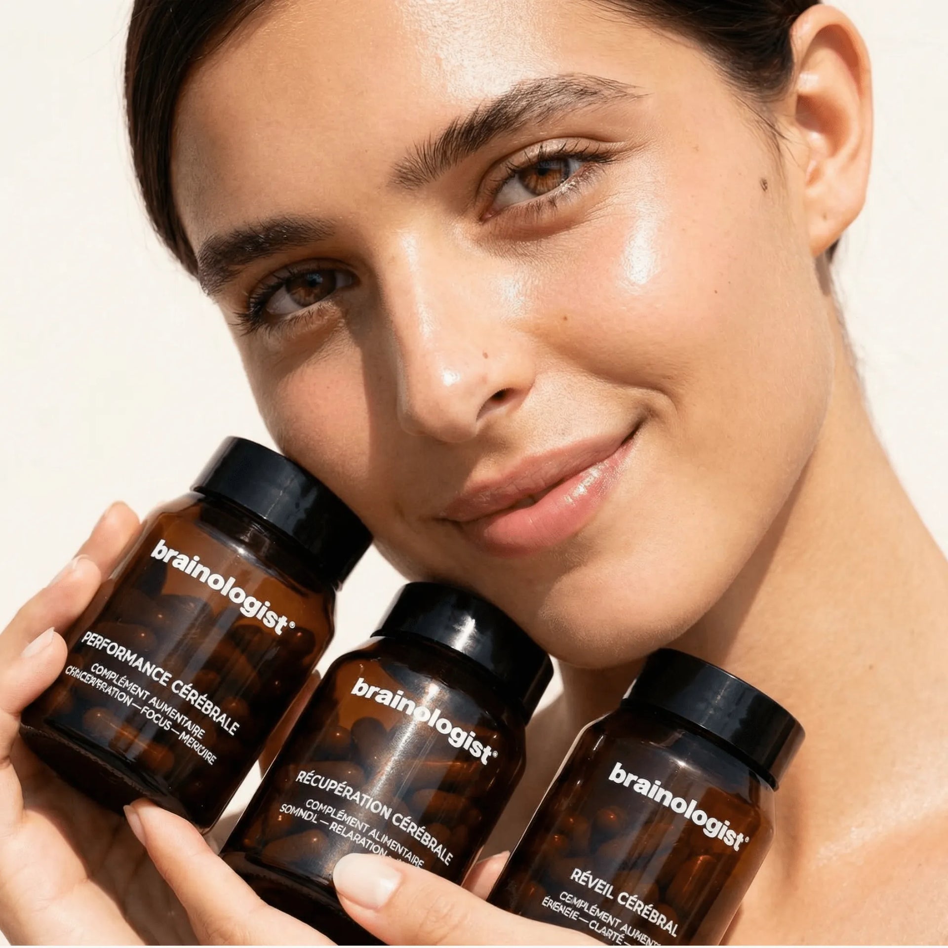 Femme tenant la routine de soin longévité 24h en entier : les flacons Réveil cérébral Performance cérébrale et Récupération cérébrale dans ses mains