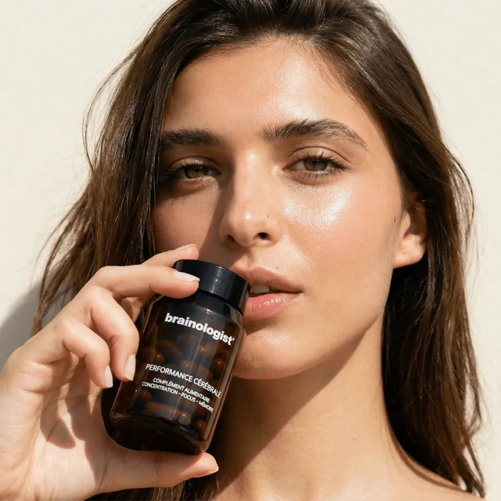 Femme tenant le flacon Performance Cérébrale Brainologist pour sa routine de concentration